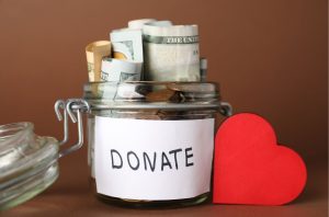 A donate jar filled with cash next to a red heart